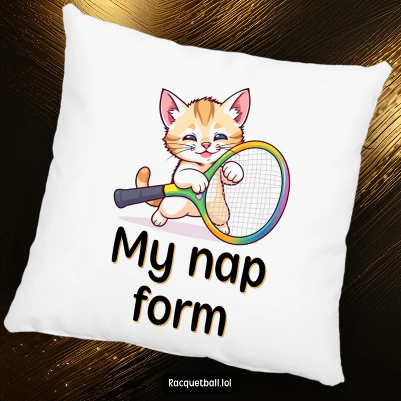 Funny kitten tripping pillow showing a cute cat comically falling over a large tennis racquet, providing comfort and humor.