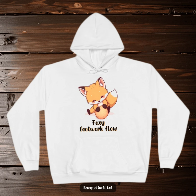 Funny hoodie featuring a playful fox cub performing a dramatic slide to return a tiny, fuzzy ball, cozy action.