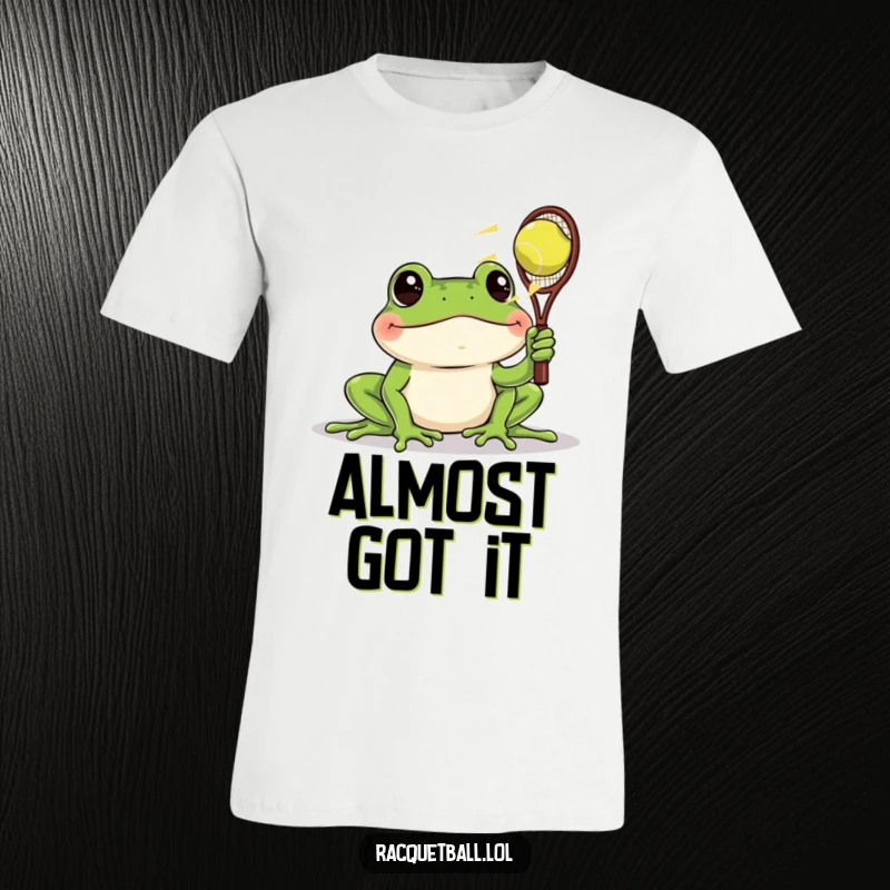 Funny t-shirt featuring a frog with startled eyes watching a racquetball whiz by, a humorous depiction of surprise and speed.