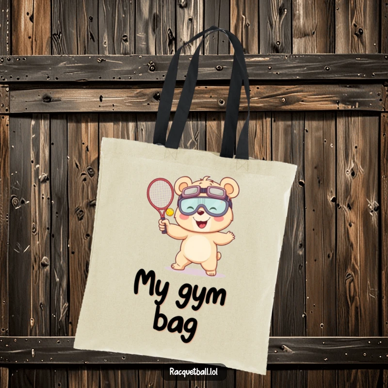 Funny tote bag featuring a giggling bear in oversized goggles, mid-serve with a racquetball, ready to carry your items with sporty humor.
